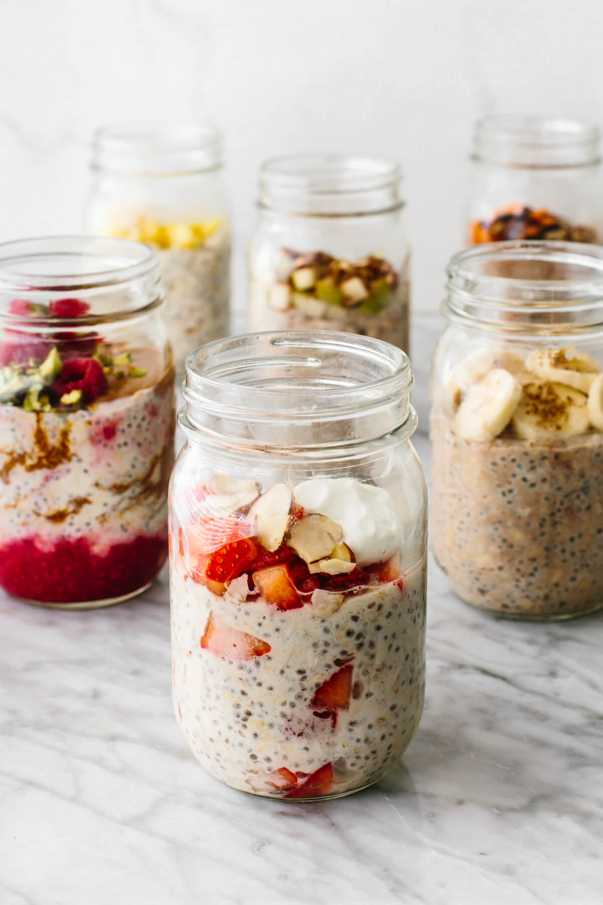 Learn how to make the perfect batch of overnight oats! It's easy, healthy, customizable, and great for grab-and-go meals. Overnight oats in a few jars with fruits on a table.